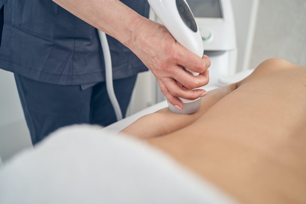 Woman undergoing ultrasound cavitation in beauty clinic